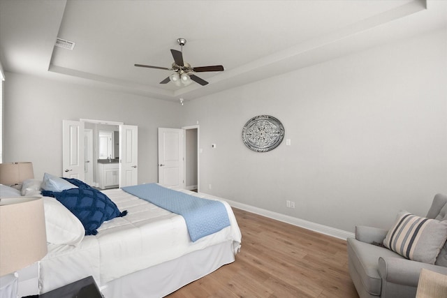 3604 Hidden Hollow Dr, Grand Prairie, TX 76065 - bedroom with a raised ceiling, baseboards, light wood finished floors, a ceiling fan, and ensuite bathroom