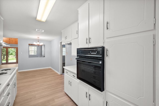 209 Circle Dr, Alvarado, TX 76009 - kitchen with black oven, a chandelier, light wood-style flooring, and white cabinetry