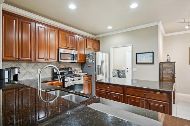 6173 Arcadia Park Ln, Frisco, TX 75036 - kitchen featuring stainless steel appliances, washer and clothes dryer, crown molding, tasteful backsplash, and dark stone counters