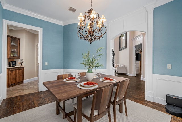 4452 Druid Hills Dr, Frisco, TX 75034 - dining area with arched walkways, a chandelier, wainscoting, ornamental molding, and light wood-type flooring