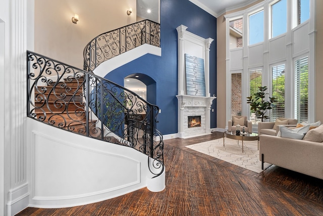 4452 Druid Hills Dr, Frisco, TX 75034 - living room featuring a towering ceiling, stairway, a lit fireplace, wood finished floors, and crown molding