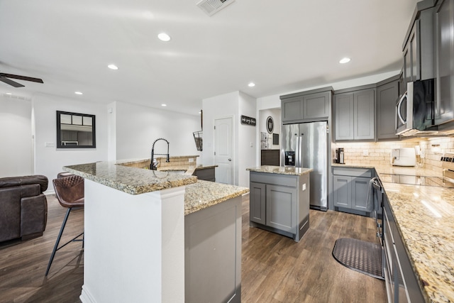 601 S 4th St, Crandall, TX 75114 - kitchen featuring a kitchen island with sink, stainless steel appliances, gray cabinetry, open floor plan, and tasteful backsplash