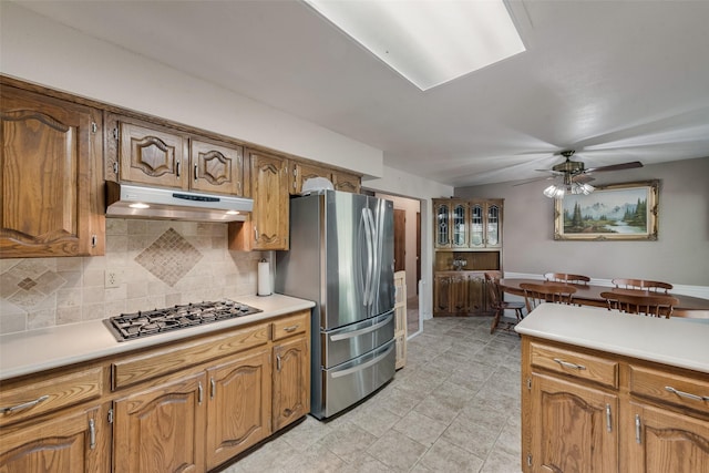 3410 Queenswood Ln, Garland, TX 75040 - kitchen featuring under cabinet range hood, gas stovetop, freestanding refrigerator, tasteful backsplash, and light countertops