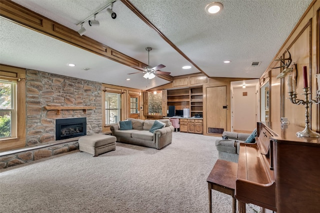 3410 Queenswood Ln, Garland, TX 75040 - carpeted living room featuring a textured ceiling, a stone fireplace, a ceiling fan, recessed lighting, and vaulted ceiling