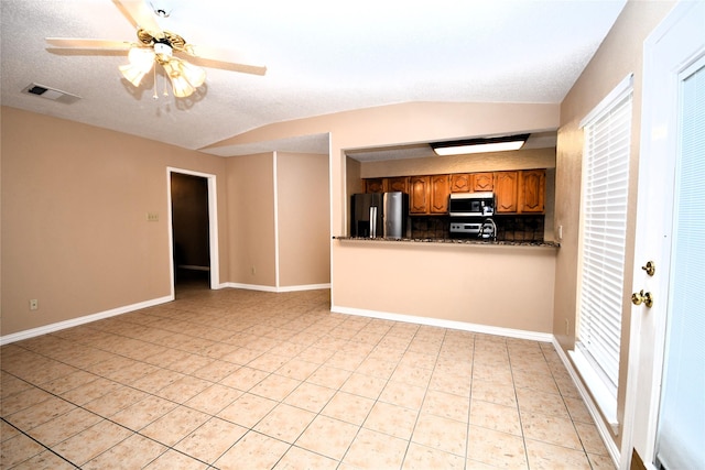 2906 Kingswood Dr, Garland, TX 75040 - kitchen with stainless steel microwave, fridge with ice dispenser, brown cabinetry, dark countertops, and light tile patterned floors