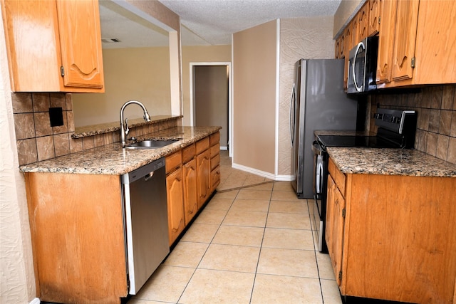 2906 Kingswood Dr, Garland, TX 75040 - kitchen with appliances with stainless steel finishes, a sink, light tile patterned flooring, light stone counters, and baseboards