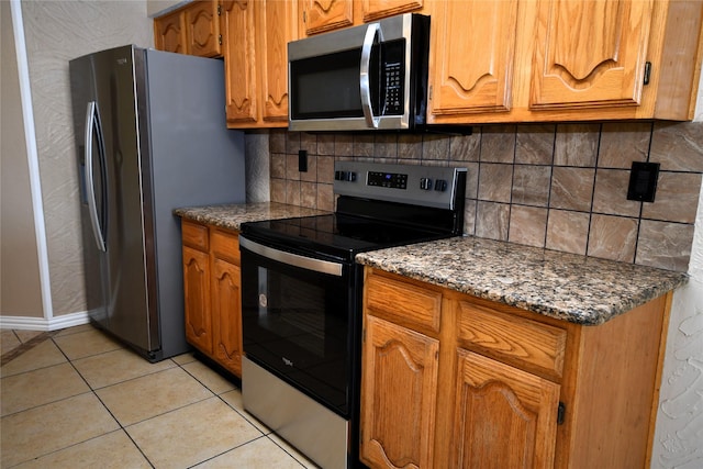 2906 Kingswood Dr, Garland, TX 75040 - kitchen featuring stainless steel appliances, tasteful backsplash, brown cabinets, and light tile patterned flooring