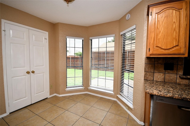 2906 Kingswood Dr, Garland, TX 75040 - unfurnished dining area featuring a textured wall, light tile patterned flooring, and baseboards