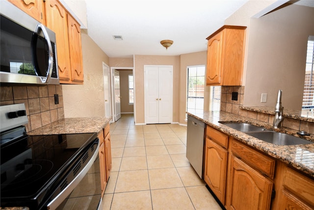 2906 Kingswood Dr, Garland, TX 75040 - kitchen featuring appliances with stainless steel finishes, a sink, decorative backsplash, light stone countertops, and light tile patterned floors