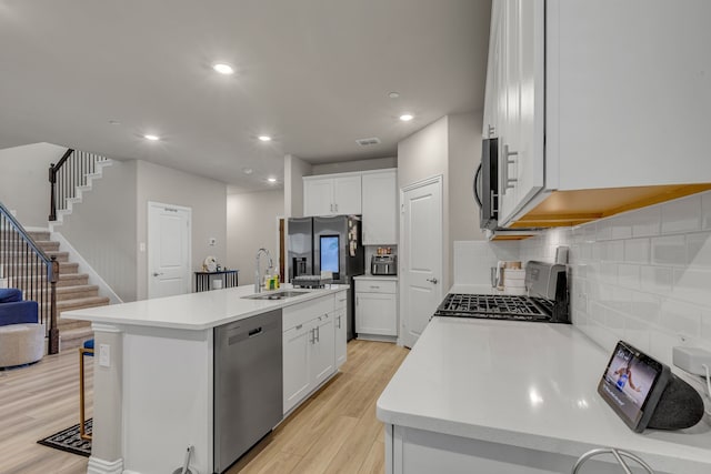 201 Olympus St, Wylie, TX 75098 - kitchen featuring appliances with stainless steel finishes, a kitchen island with sink, light wood-type flooring, a sink, and tasteful backsplash