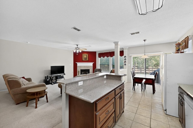 848 Ridge Point Dr, Grand Prairie, TX 75052 - kitchen featuring freestanding refrigerator, ceiling fan, open floor plan, a tile fireplace, and decorative columns
