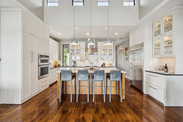 4003 Cheyenne Cir, Flower Mound, TX 75022 - kitchen with stainless steel appliances, tasteful backsplash, a center island with sink, a towering ceiling, and white cabinets