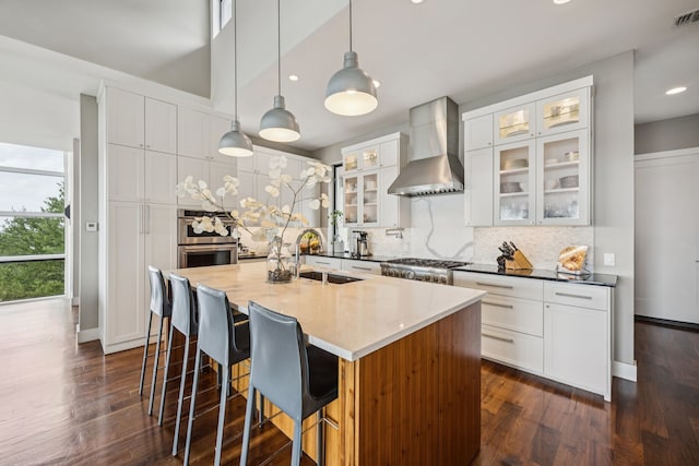 4003 Cheyenne Cir, Flower Mound, TX 75022 - kitchen with wall chimney exhaust hood, a sink, tasteful backsplash, a center island with sink, and dark wood-style flooring