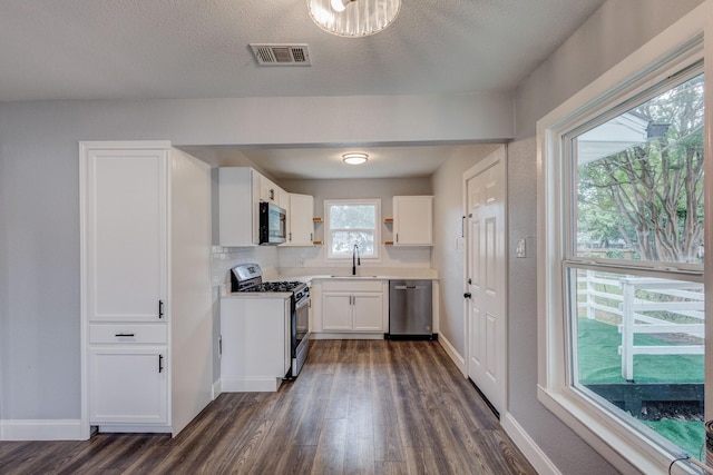308 Chandler Dr, Garland, TX 75040 - kitchen featuring appliances with stainless steel finishes, dark wood-style floors, a sink, white cabinets, and baseboards