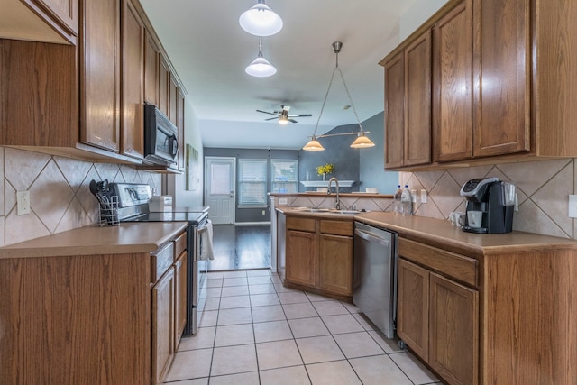 2111 Preston Trl, Forney, TX 75126 - kitchen with stainless steel appliances, a sink, a ceiling fan, brown cabinetry, and a peninsula