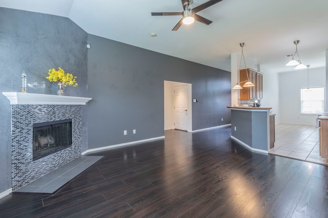 2111 Preston Trl, Forney, TX 75126 - unfurnished living room with wood finished floors, ceiling fan, a tiled fireplace, baseboards, and high vaulted ceiling