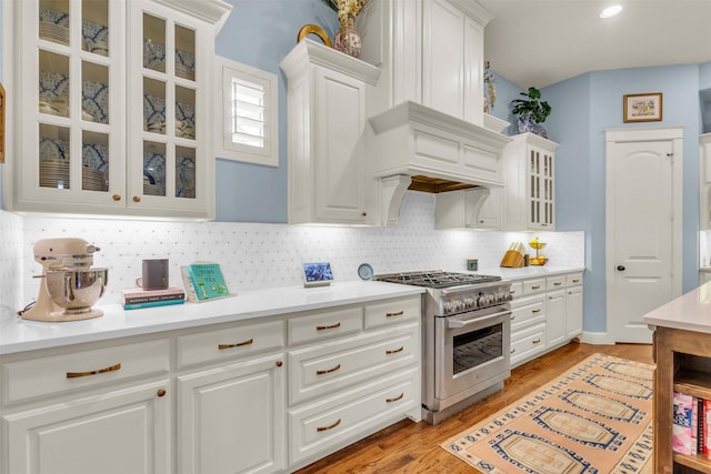 2116 Tremont Blvd, Mckinney, TX 75071 - kitchen featuring high end stove, white cabinets, backsplash, glass insert cabinets, and light countertops