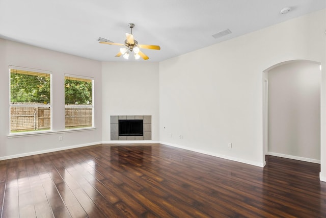 13209 Fencerow Rd, Fort Worth, TX 76244 - unfurnished living room featuring arched walkways, wood finished floors, ceiling fan, baseboards, and a fireplace