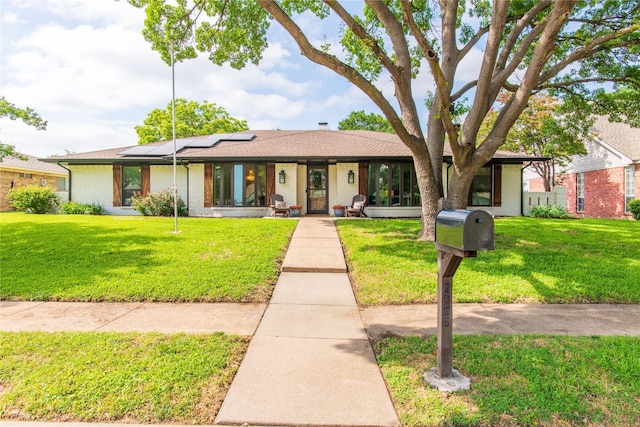 2725 Regal Rd, Plano, TX 75075 - ranch-style house with roof mounted solar panels, brick siding, and a front lawn