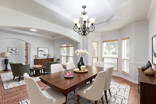 3436 Copper Point Ln, Frisco, TX 75034 - dining space featuring a tray ceiling, arched walkways, a chandelier, baseboards, and wood finished floors