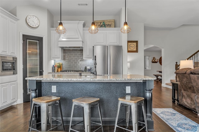 1925 Knoxbridge Rd, Forney, TX 75126 - kitchen with stainless steel appliances, decorative backsplash, arched walkways, dark wood-type flooring, and light stone counters