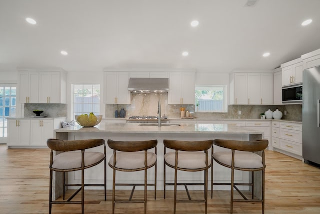 4336 Irvin Simmons Dr, Dallas, TX 75229 - kitchen featuring black microwave, exhaust hood, backsplash, freestanding refrigerator, and a kitchen island with sink