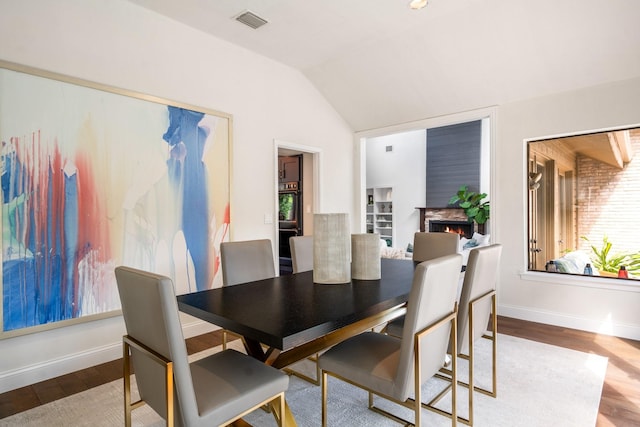 5325 Seascape Ln, Plano, TX 75093 - dining space featuring vaulted ceiling, wood finished floors, plenty of natural light, baseboards, and a warm lit fireplace