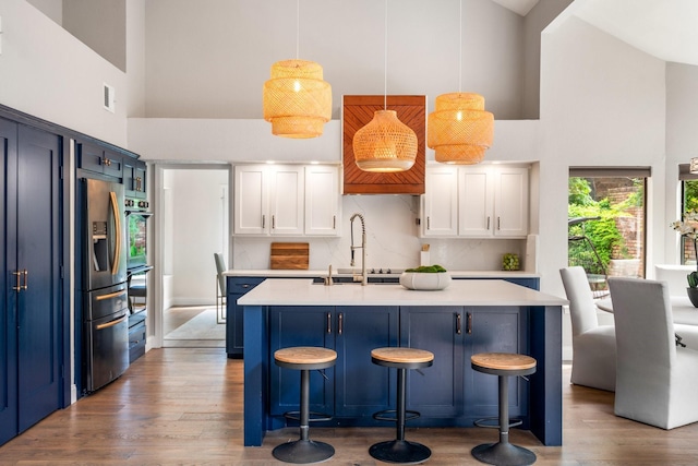5325 Seascape Ln, Plano, TX 75093 - kitchen featuring high vaulted ceiling, stainless steel refrigerator with ice dispenser, blue cabinets, a sink, and wood finished floors