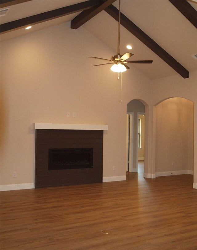 701 Raylan St, Springtown, TX 76082 - unfurnished living room with beam ceiling, wood finished floors, arched walkways, a fireplace, and baseboards