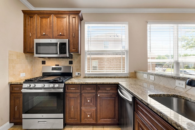 7603 Cousteau Dr, Rowlett, TX 75088 - kitchen with stainless steel appliances, a sink, decorative backsplash, light stone counters, and crown molding