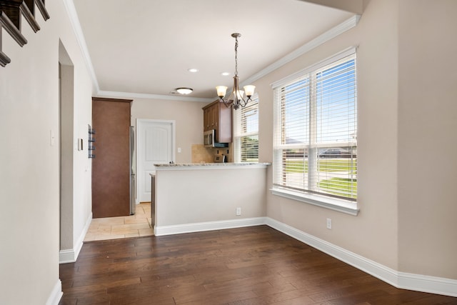 7603 Cousteau Dr, Rowlett, TX 75088 - kitchen featuring stainless steel microwave, a chandelier, hardwood / wood-style flooring, crown molding, and baseboards