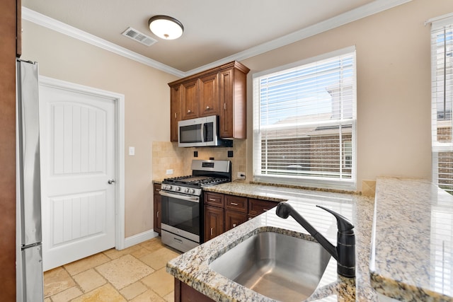 7603 Cousteau Dr, Rowlett, TX 75088 - kitchen featuring stainless steel appliances, a sink, ornamental molding, tasteful backsplash, and light stone countertops