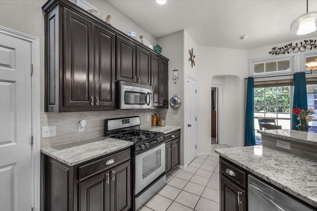 5212 Cross Timber Rd W, Cleburne, TX 76031 - kitchen with appliances with stainless steel finishes, light tile patterned floors, arched walkways, tasteful backsplash, and light stone countertops