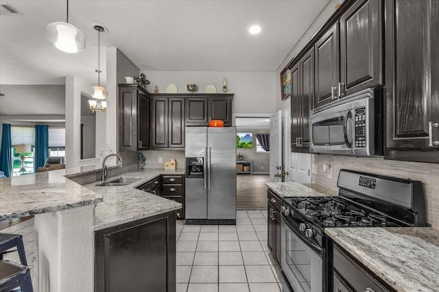5212 Cross Timber Rd W, Cleburne, TX 76031 - kitchen featuring stainless steel appliances, backsplash, light stone countertops, a peninsula, and decorative light fixtures