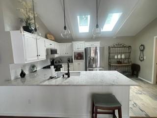 2510 Plumdale Dr, Carrollton, TX 75006 - kitchen featuring appliances with stainless steel finishes, a peninsula, lofted ceiling, a skylight, and white cabinetry