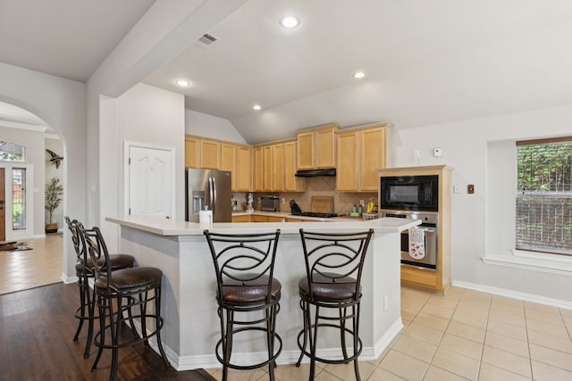 107 Barkley Dr, Hickory Creek, TX 75065 - kitchen featuring black appliances, light brown cabinetry, light countertops, a breakfast bar area, and lofted ceiling