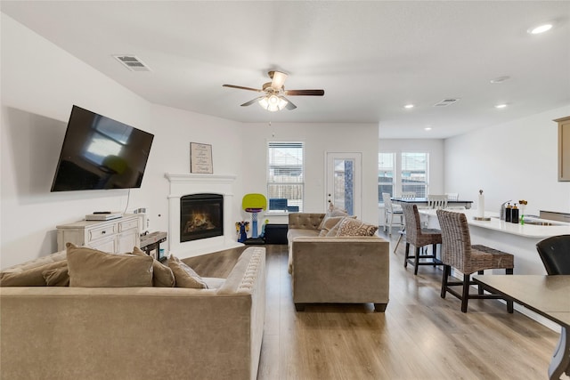10407 Twisting Springs Dr, Aubrey, TX 76227 - living area featuring light wood-style flooring, ceiling fan, a fireplace with flush hearth, and recessed lighting