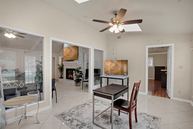 9718 Burney Dr, Dallas, TX 75243 - home office with ceiling fan, a skylight, vaulted ceiling, a fireplace, and light tile patterned floors