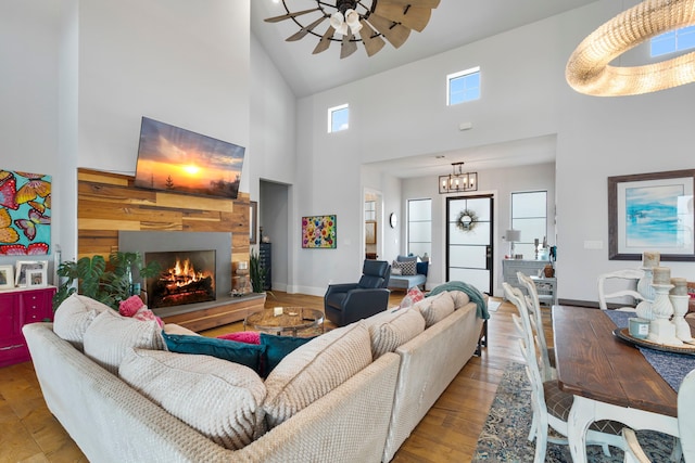 1234 Shelby Ln, Celina, TX 75009 - living room with a towering ceiling, a lit fireplace, ceiling fan, wood finished floors, and a chandelier