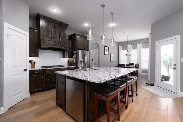 2113 Twin Creeks Cir, Pilot Point, TX 76258 - kitchen featuring stainless steel refrigerator with ice dispenser, light wood finished floors, tasteful backsplash, light stone counters, and a kitchen bar