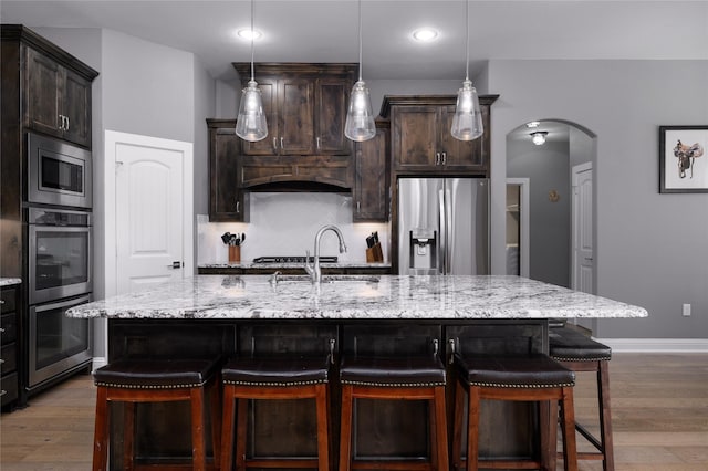 2113 Twin Creeks Cir, Pilot Point, TX 76258 - kitchen featuring stainless steel appliances, arched walkways, a sink, wood finished floors, and recessed lighting