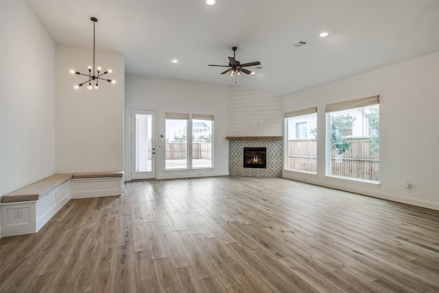 8235 Ottowa Rdg, Frisco, TX 75034 - unfurnished living room featuring ceiling fan, light wood-type flooring, a tiled fireplace, a chandelier, and high vaulted ceiling