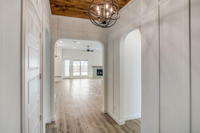 8235 Ottowa Rdg, Frisco, TX 75034 - hall featuring a chandelier, arched walkways, light wood-style flooring, baseboards, and wooden ceiling