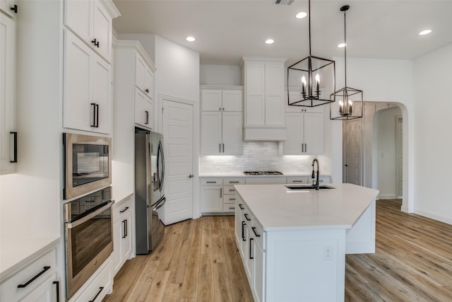 8235 Ottowa Rdg, Frisco, TX 75034 - kitchen featuring stainless steel appliances, light wood-style floors, arched walkways, backsplash, and recessed lighting