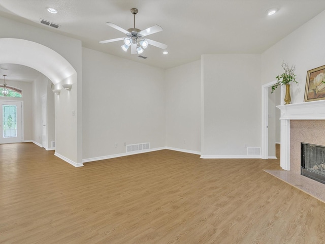 1536 Valley Creek Rd, Denton, TX 76205 - unfurnished living room featuring wood finished floors, arched walkways, a fireplace with flush hearth, a ceiling fan, and recessed lighting