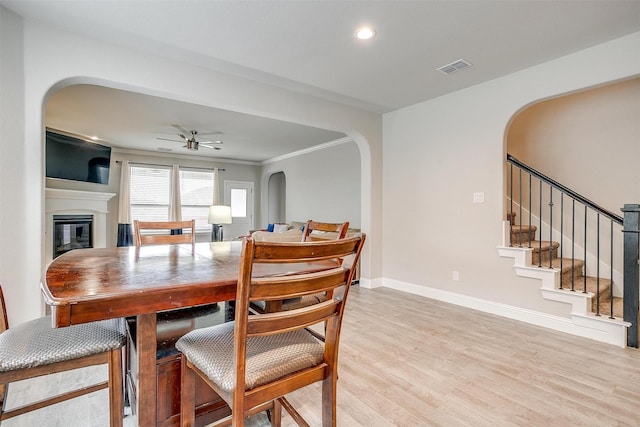 240 Gill Point Ln, Aledo, TX 76008 - dining area with arched walkways, a glass covered fireplace, light wood finished floors, ceiling fan, and baseboards