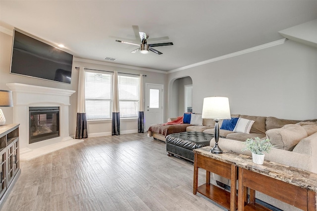 240 Gill Point Ln, Aledo, TX 76008 - living area featuring arched walkways, a ceiling fan, crown molding, a glass covered fireplace, and light wood-style flooring