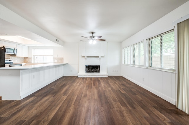 3113 E Park Blvd, Plano, TX 75074 - unfurnished living room with a ceiling fan, dark wood-style flooring, a sink, a brick fireplace, and healthy amount of natural light