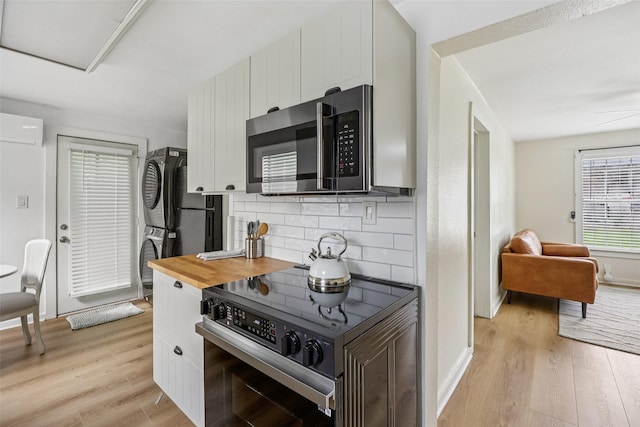 604 N Benge St, Mckinney, TX 75069 - kitchen featuring stainless steel microwave, electric range, a wall mounted air conditioner, light wood-style flooring, and backsplash