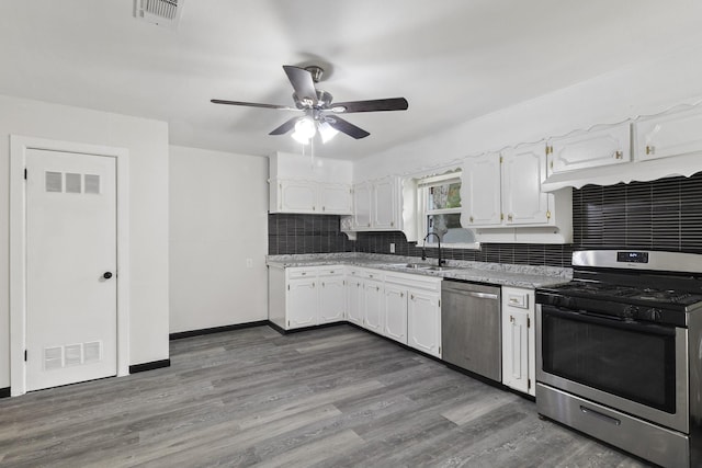 224 Brown Trl, Hurst, TX 76053 - kitchen featuring appliances with stainless steel finishes, a sink, white cabinetry, decorative backsplash, and dark wood-type flooring